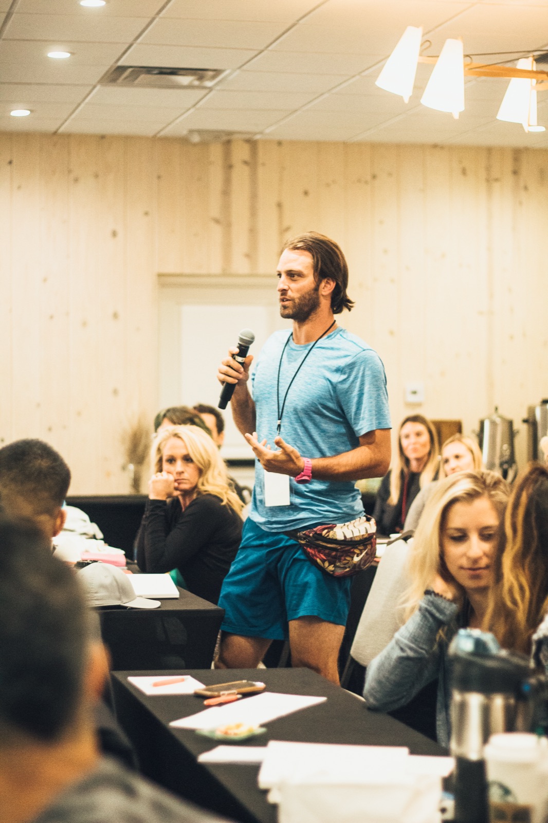Zach on the mic, mid-talk — fanny pack on the hip, watch on the wrist